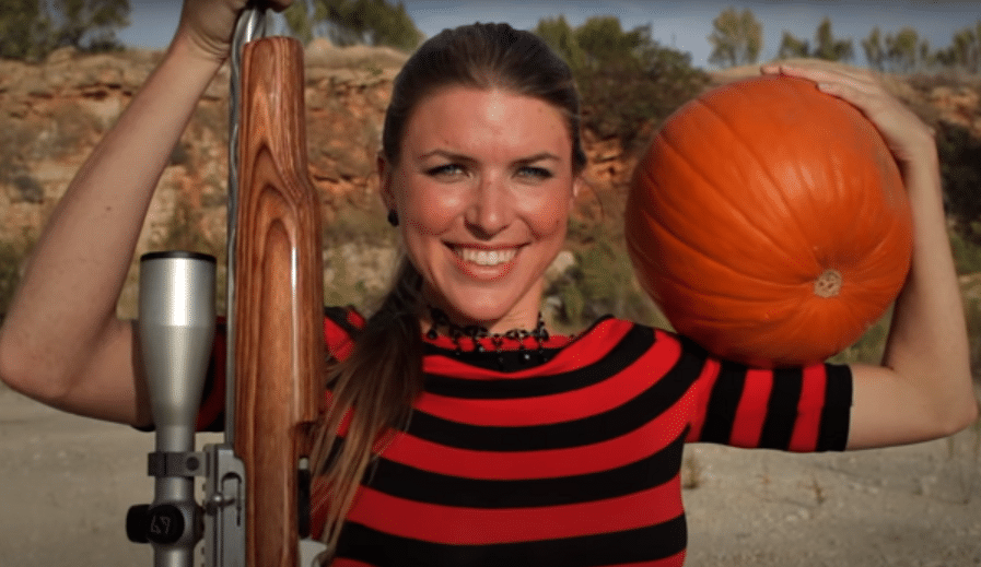 woman teaching people how to carve a pumpkin with a handgun